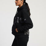 Person wearing a black hoodie with gray patterns on a white background