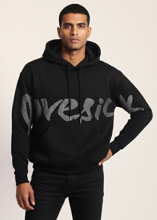 Man wearing a black hoodie with 'GUESS' branding on a light background
