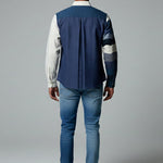 Person wearing a blue and white jacket with jeans on a gray background