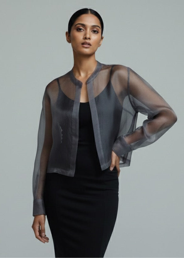 Woman wearing a sheer black jacket over a black dress on a gray background