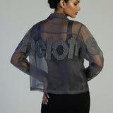 Woman wearing a sheer black top with 'HOLLY' text on a plain background