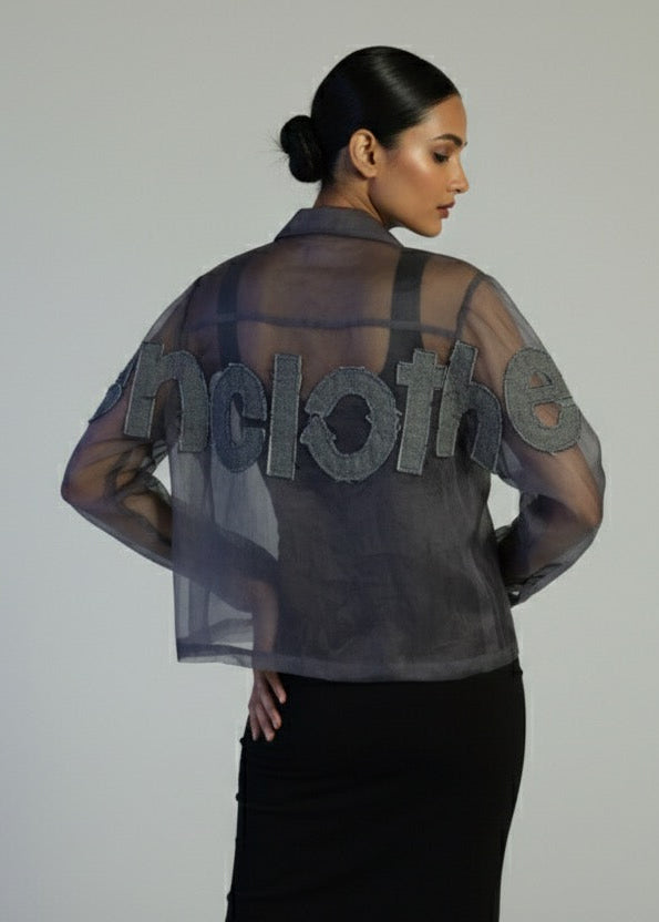 Woman wearing a sheer black top with 'HOLLY' text on a plain background
