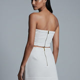 Woman wearing a white strapless dress against a gray background