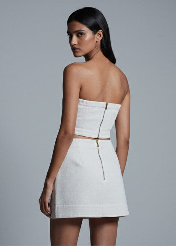 Woman wearing a white strapless dress against a gray background
