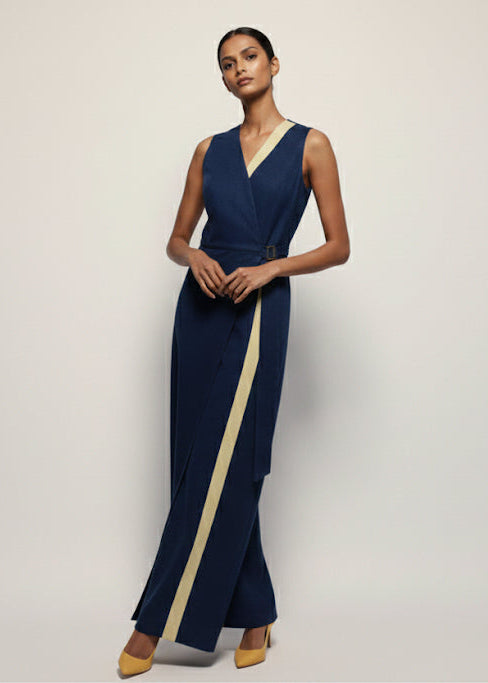 Woman wearing a navy evening gown with a gold stripe on a plain background