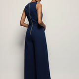 Woman wearing a navy blue jumpsuit on a plain background