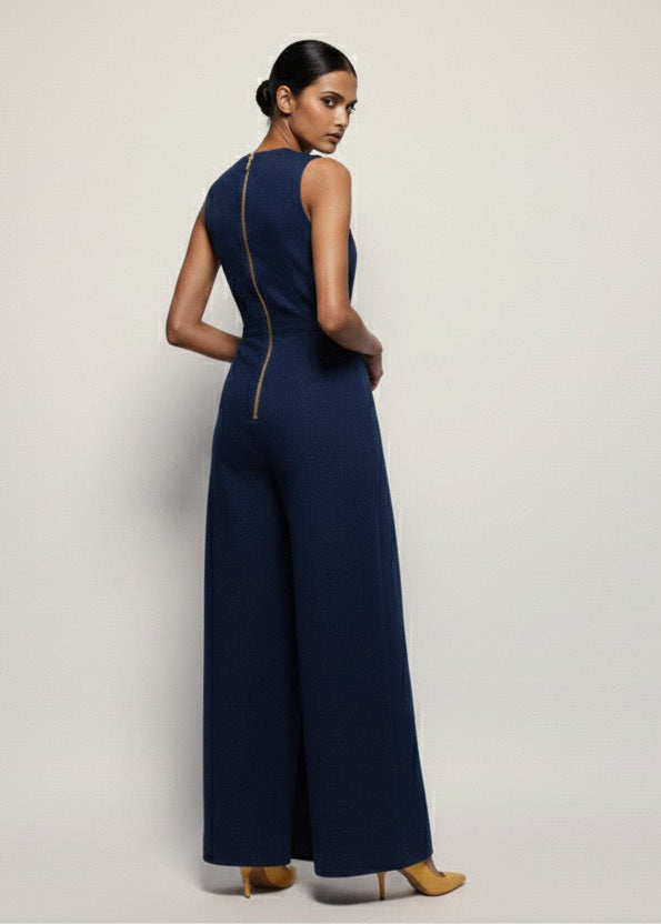 Woman wearing a navy blue jumpsuit on a plain background