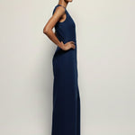 Woman wearing a long navy blue dress against a plain background