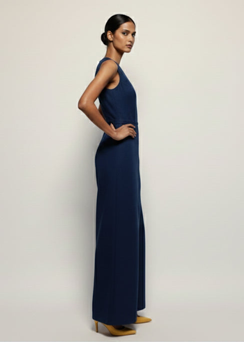 Woman wearing a long navy blue dress against a plain background