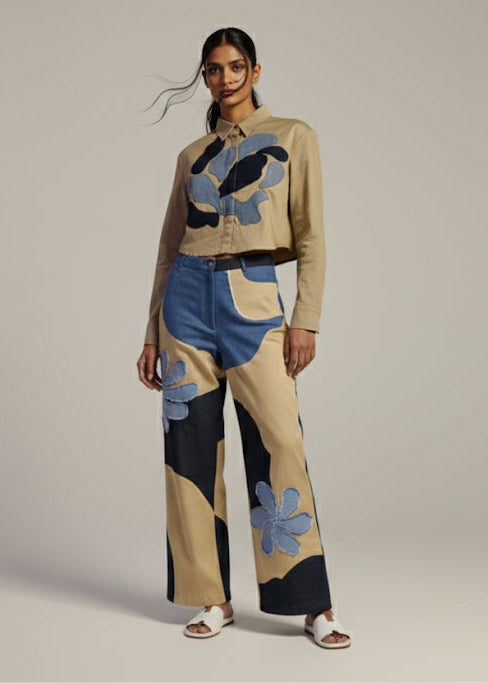 Woman wearing a stylish outfit with floral patterns on a plain background