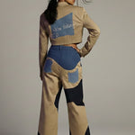 Woman wearing a stylish outfit with a patterned jacket and pants on a plain background