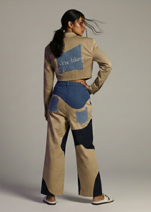 Woman wearing a stylish outfit with a patterned jacket and pants on a plain background