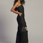 Woman wearing a black strapless jumpsuit with colorful text design on a plain background