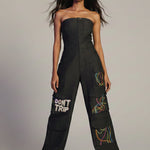Woman wearing a black jumpsuit with text and patterns on a plain background