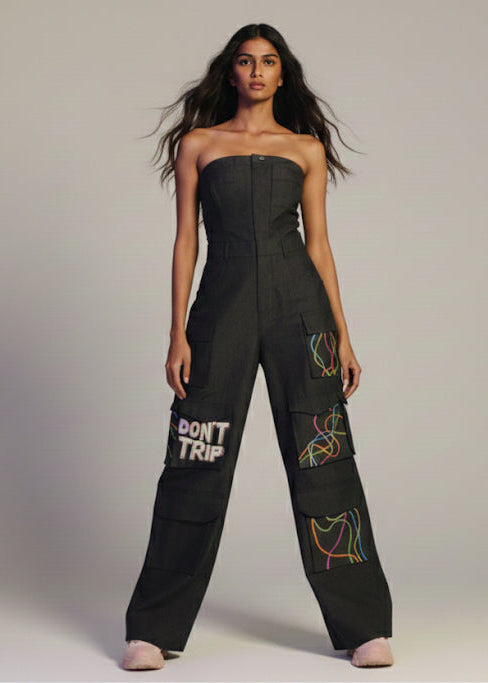 Woman wearing a black jumpsuit with text and patterns on a plain background