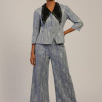Woman wearing a denim suit with black accents on a plain background