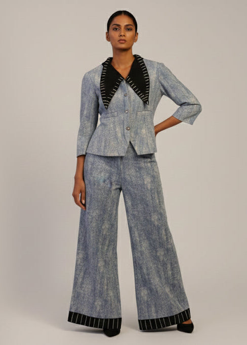Woman wearing a denim suit with black accents on a plain background