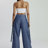 Woman wearing a strapless top and blue wide-leg pants on a white background