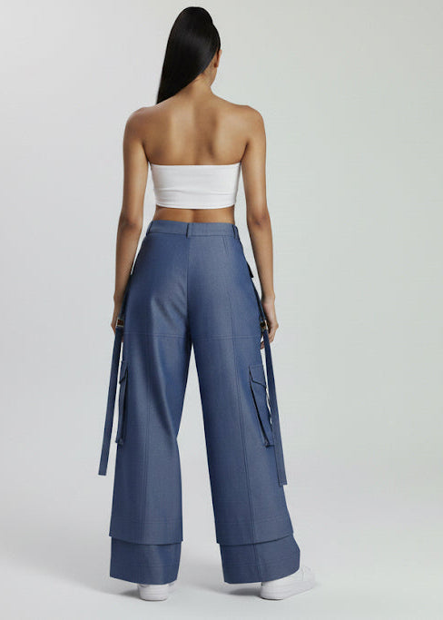 Woman wearing a strapless top and blue wide-leg pants on a white background
