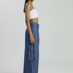 Woman wearing a white top and blue cargo pants on a white background