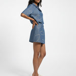 Woman wearing a blue denim outfit with cloud patterns on a white background