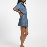 Woman wearing a blue denim outfit with cloud patterns on a white background