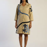 Woman wearing a beige dress with blue floral patterns on a white background