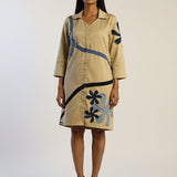 Woman wearing a beige dress with blue floral patterns on a white background