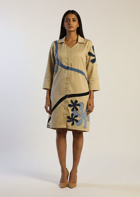 Woman wearing a beige dress with blue floral patterns on a white background