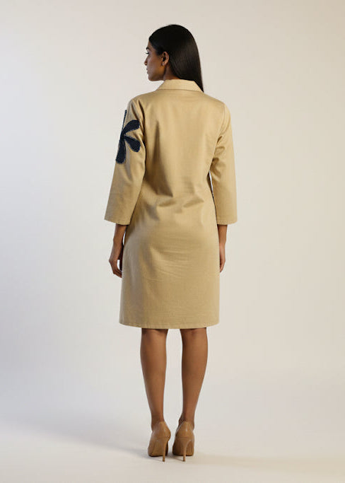 Woman wearing a beige suit with a black design on the back against a white background
