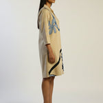 Woman wearing a beige dress with abstract patterns on a white background