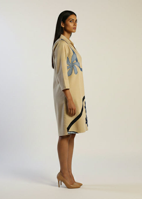 Woman wearing a beige dress with abstract patterns on a white background
