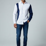 Man wearing a white shirt with navy accents and blue jeans on a gray background