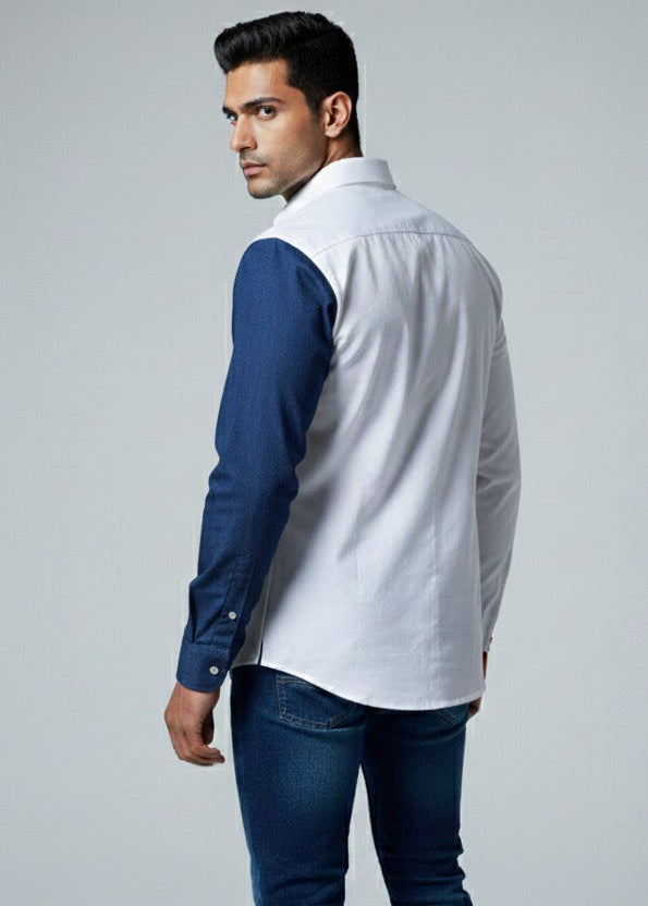 Man wearing a white shirt with blue sleeves and jeans on a gray background