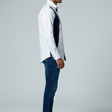 Man wearing a white shirt, dark vest, and blue jeans on a gray background