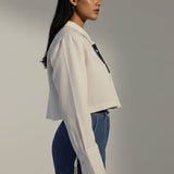 Woman wearing a white shirt and blue jeans against a plain background