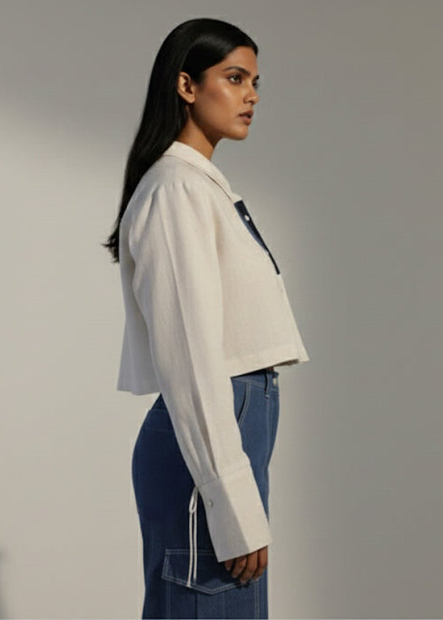 Woman wearing a white shirt and blue jeans against a plain background