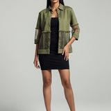 Woman wearing a green jacket over a black dress on a gray background