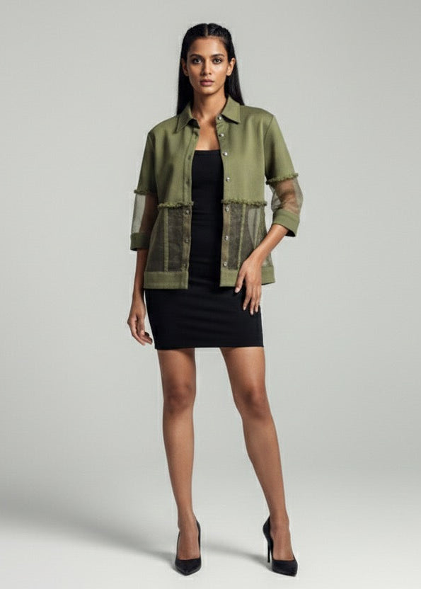 Woman wearing a green jacket over a black dress on a gray background