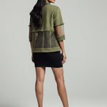 Woman wearing a green jacket and black skirt on a gray background
