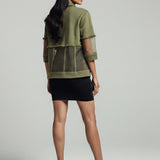 Woman wearing a green jacket and black skirt on a gray background