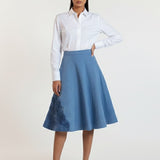 Woman wearing a white shirt and blue skirt on a white background