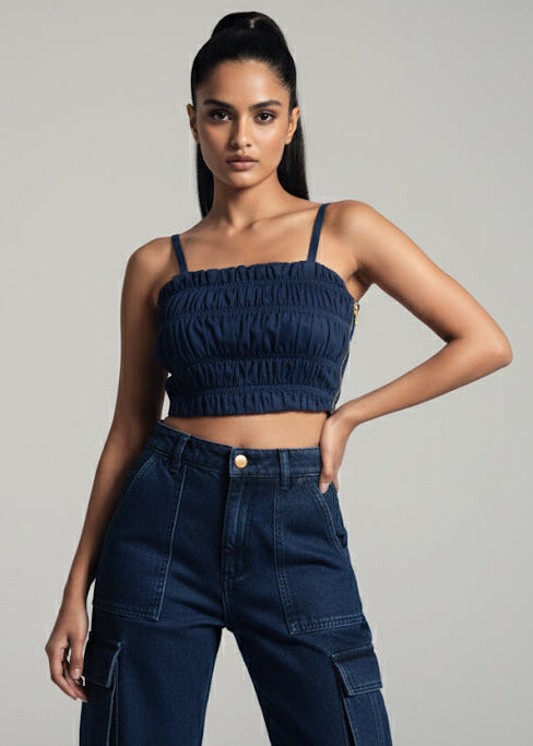 Woman wearing a navy blue crop top and high-waisted jeans against a gray background