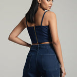 Woman wearing a navy blue sleeveless top and cargo pants on a gray background