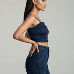 Woman wearing a dark blue strapless top and jeans on a gray background