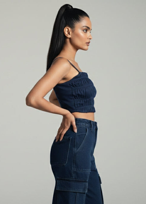 Woman wearing a dark blue strapless top and jeans on a gray background