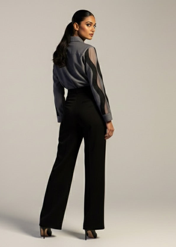 Woman wearing a black outfit with sheer sleeves against a plain background
