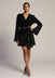 Woman wearing a black dress with star patterns on a plain background