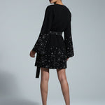 Woman wearing a black dress with star patterns on a gray background