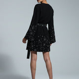 Woman wearing a black dress with star patterns on a gray background